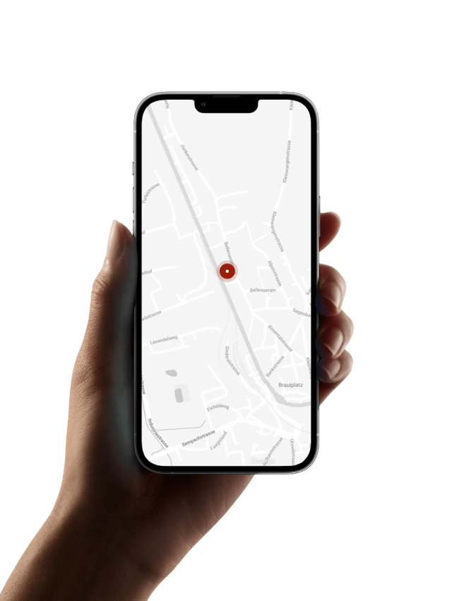 Hand hält ein Smartphone mit einer Karte auf dem Bildschirm und einem markierten Standort.